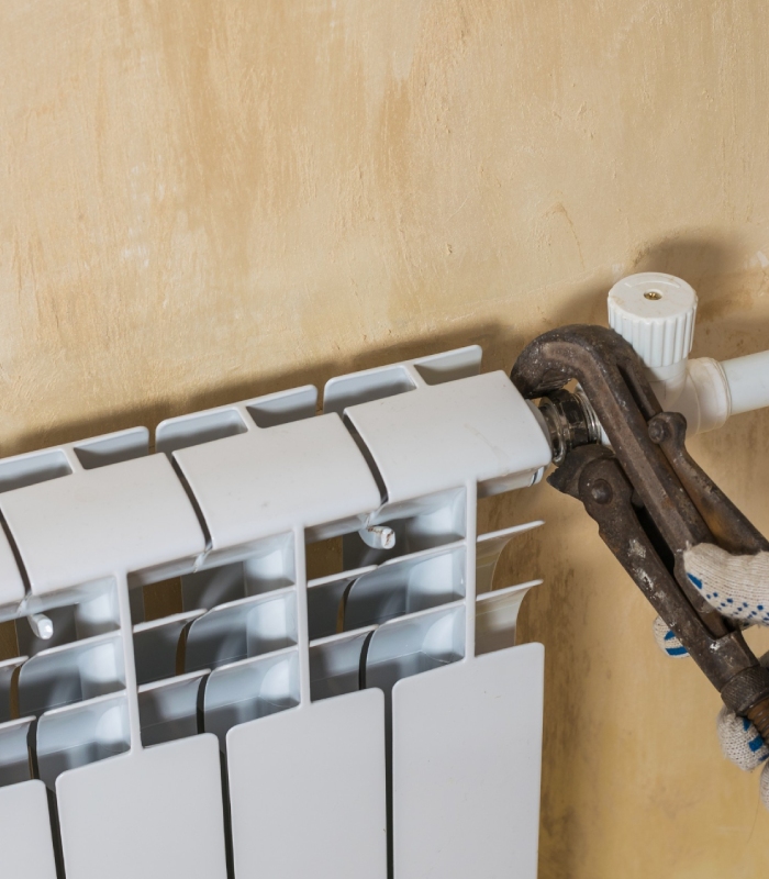 Plombier chauffagiste effectuant l’entretien d’un radiateur, maintenance et installation de chauffage Griffon Multiservices