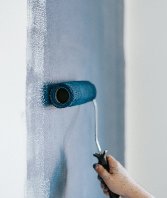 Peintre appliquant une peinture bleue sur un mur intérieur lors de travaux de rénovation Griffon Multiservices
